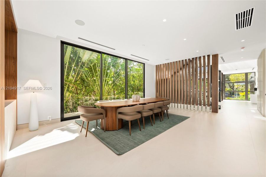 Floor-to-ceiling windows, light-toned flooring, recessed lighting, and a wood-slat partition
