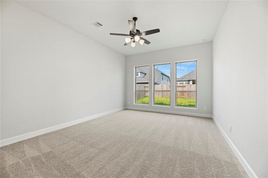 Primary bedroom offers plush carpet, ceiling fan and an en-suite bathroom.