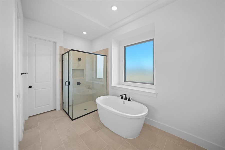 Full bathroom featuring a stall shower, a freestanding tub, light tile patterned floors, and recessed lighting