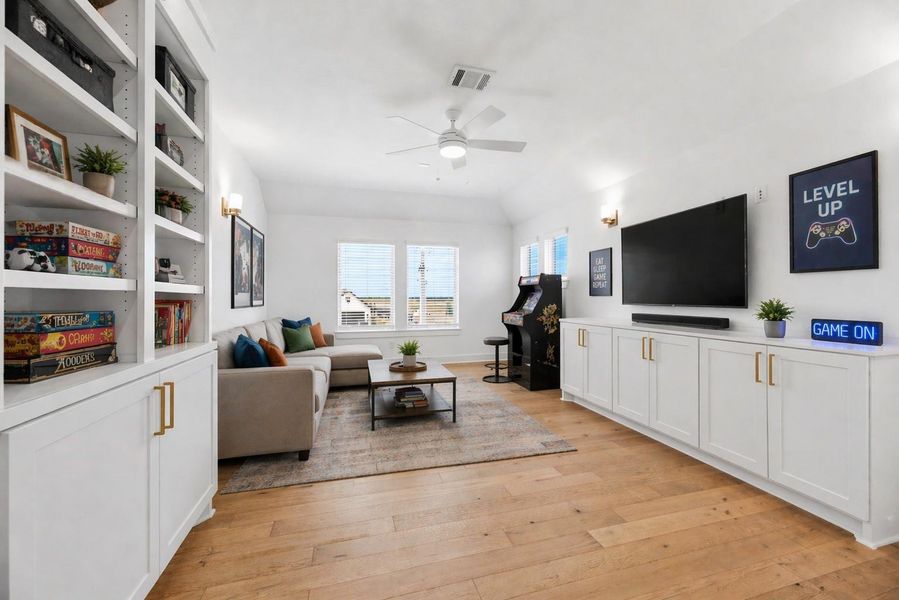 This spacious upstairs gameroom serves as the ultimate flex space, featuring custom built-in cabinetry, beautiful flooring, and ample room for media or play. Virtually staged.