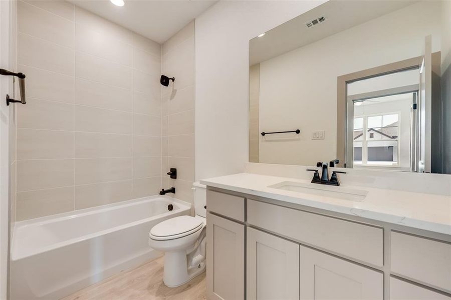 Full bathroom featuring vanity, wood-type flooring, toilet, and tiled shower / bath