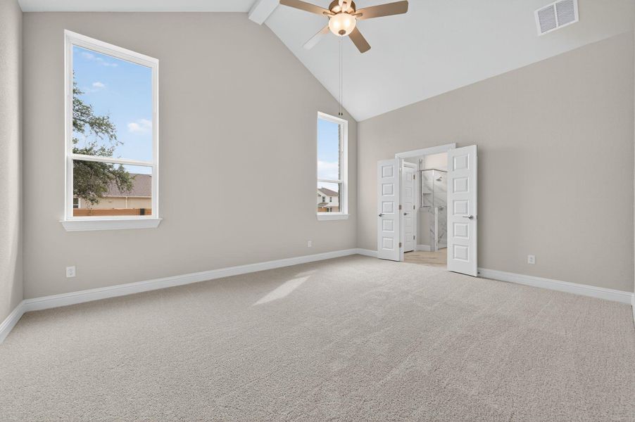 Unfurnished bedroom with light colored carpet, beamed ceiling, high vaulted ceiling, and a ceiling fan