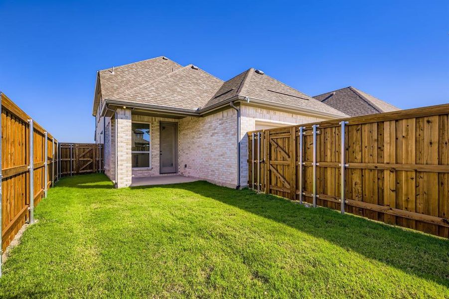 Back of property with a gate, a shingled roof, brick siding, a patio area, and a fenced backyard Back of property with a gate, a shingled roof, brick siding, a patio area, and a fenced backyard