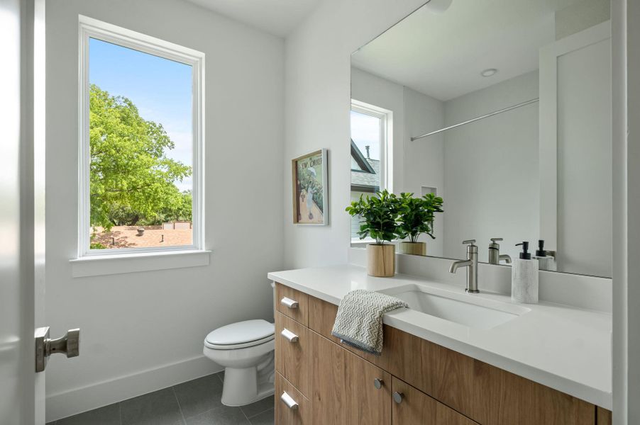 A chic bathroom offers a spacious vanity, toilet, and an abundance of natural light from a large window. A chic bathroom offers a spacious vanity, toilet, and an abundance of natural light from a large window.