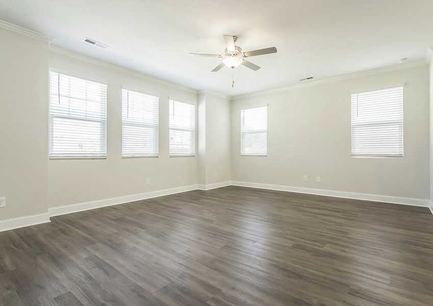 Living room with vinyl plank flooring, tons of windows and a ceiling fan.