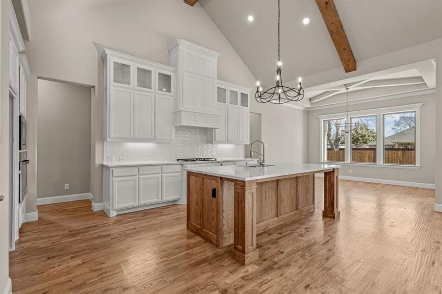 Kitchen featuring white cabinetry, pendant lighting, an island with sink, and beamed ceiling