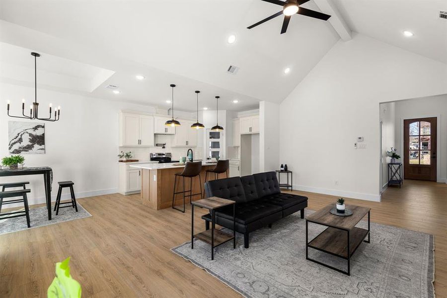 Living area with light wood-style floors, beam ceiling, visible vents, and baseboards