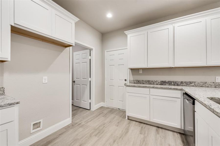 Kitchen featuring light hardwood / wood-style floors, dishwasher, and white cabinets