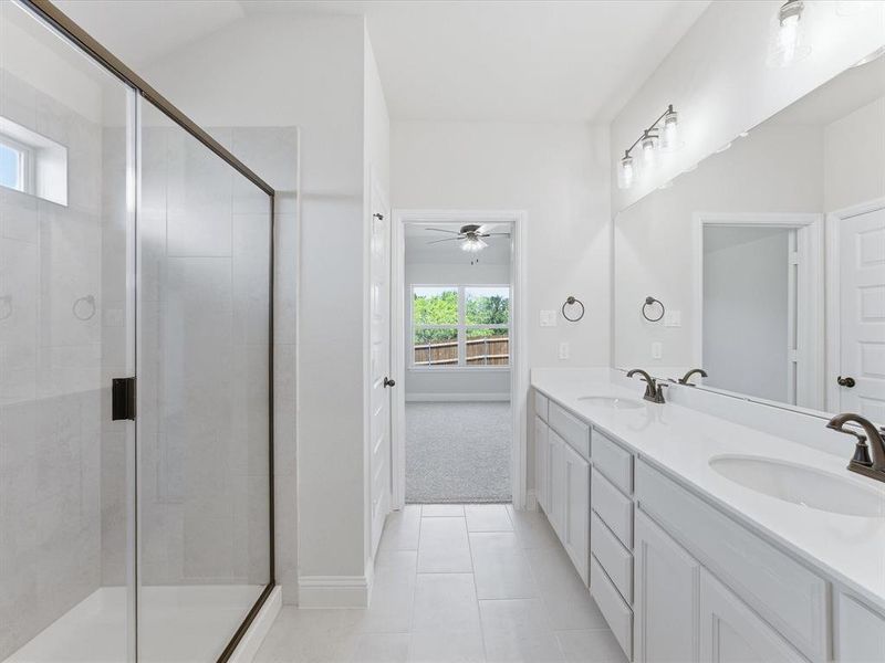 Bathroom featuring a walk-in shower with a frameless glass enclosure, dual vanity with undermount sinks, bronze finish plumbing fixtures, and tile flooring Bathroom featuring a walk-in shower with a frameless glass enclosure, dual vanity with undermount sinks, bronze finish plumbing fixtures, and tile flooring