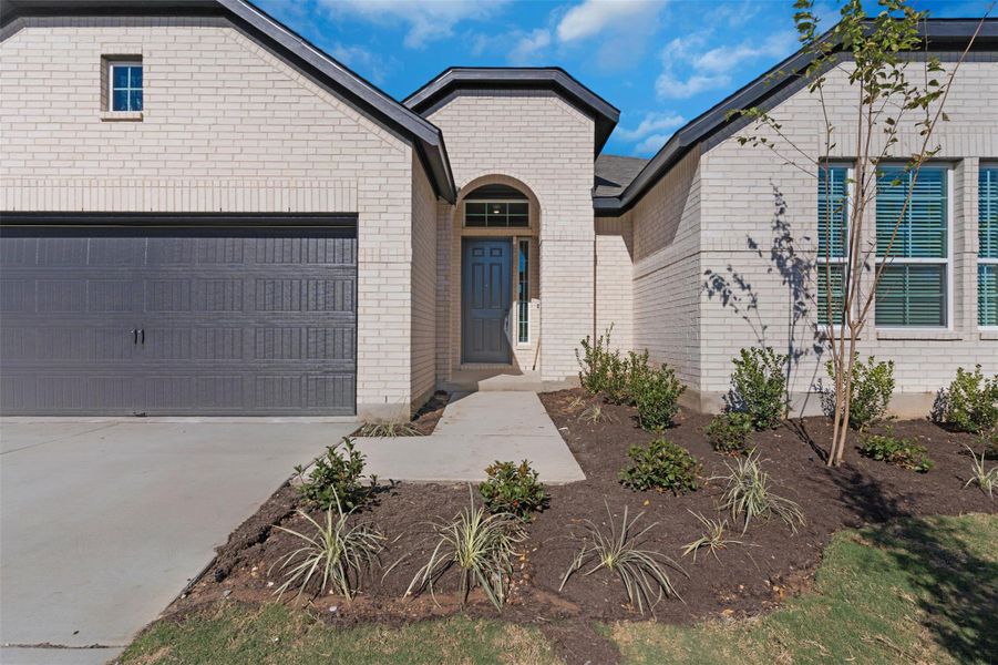 View of front of home featuring an attached garage, concrete driveway, and brick siding