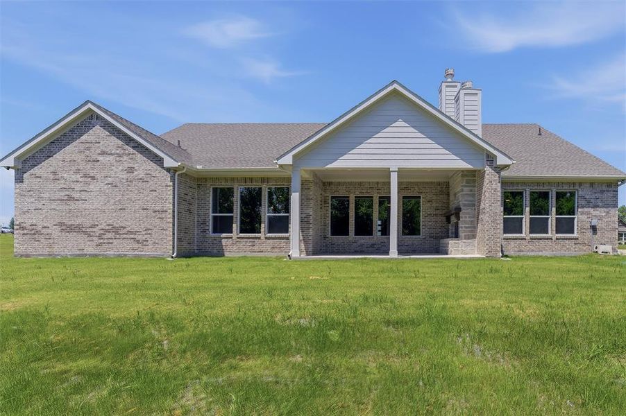 Rear exterior featuring a covered patio, extensive window array, and brick facade