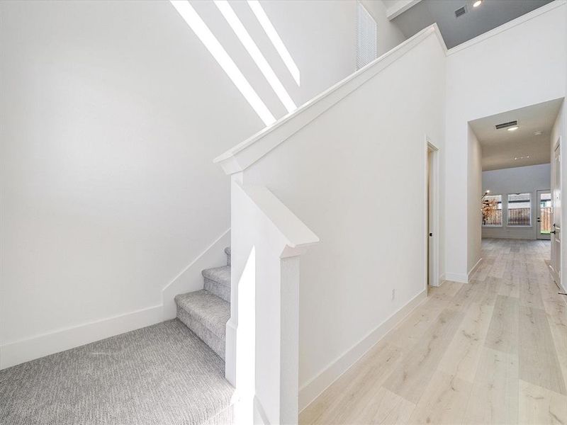 Stairs with wood finished floors and a high ceiling