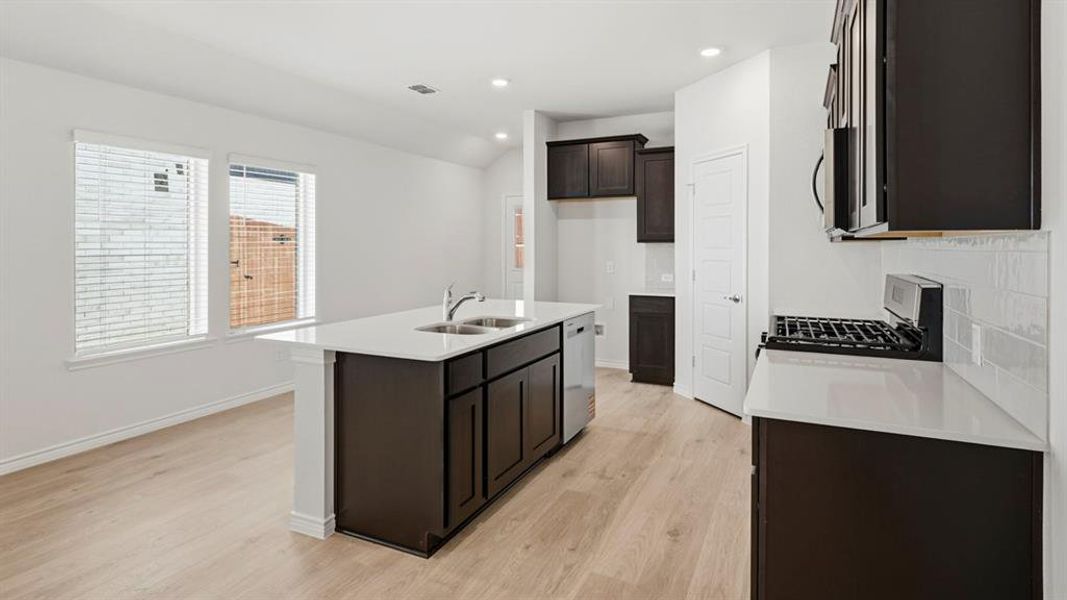 Kitchen featuring light stone counters, light wood-style floors, stainless steel appliances, recessed lighting, and lofted ceiling