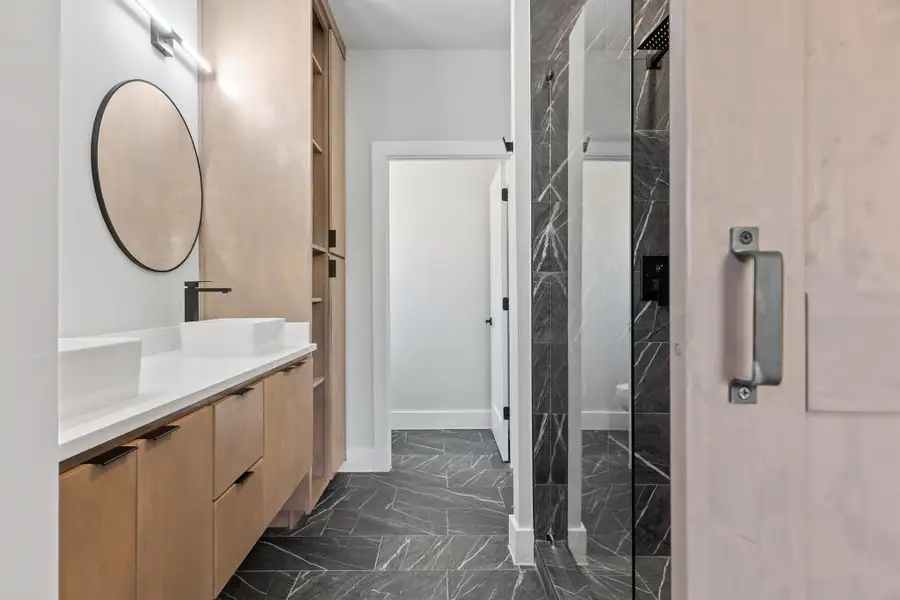 Bathroom featuring dark marble finish flooring, double vanity, and a marble finish shower