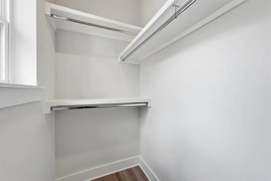 Walk-in closet with built-in shelving and hanging space, offering efficient storage in a clean, modern setting.