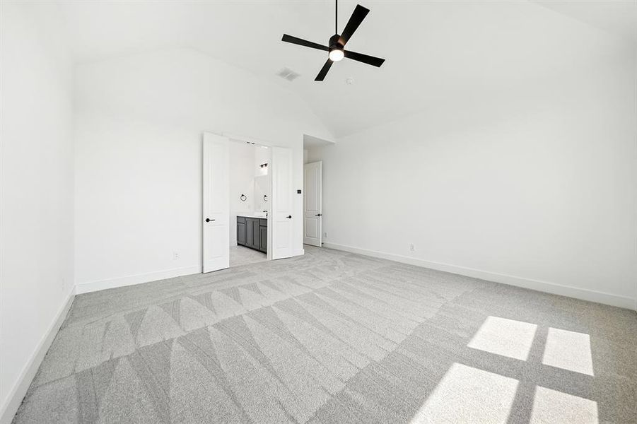 Unfurnished bedroom featuring light colored carpet, ceiling fan, high vaulted ceiling, and ensuite bathroom