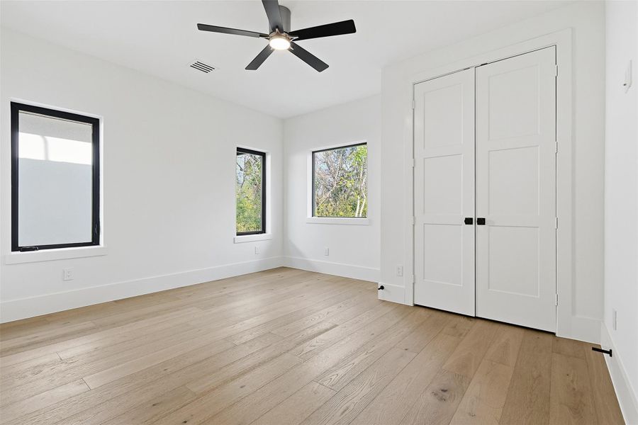 Dual large windows provide ample natural light to this bedroom, which also includes a spacious double-door closet.