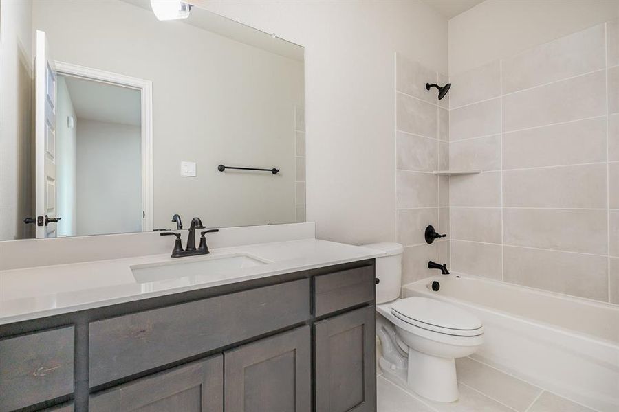 Full bathroom featuring vanity, toilet, tile patterned flooring, and tiled shower / bath