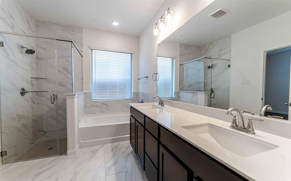 Spacious bathroom featuring a dual vanity with undermount sinks and extensive countertop space, a walk-in shower with a glass enclosure and bench, a separate soaking tub, and elegant marble-finish tile flooring