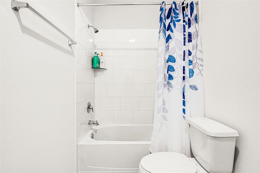 Bright bathroom layout featuring a clean tub and shower combination with a decorative shower curtain.