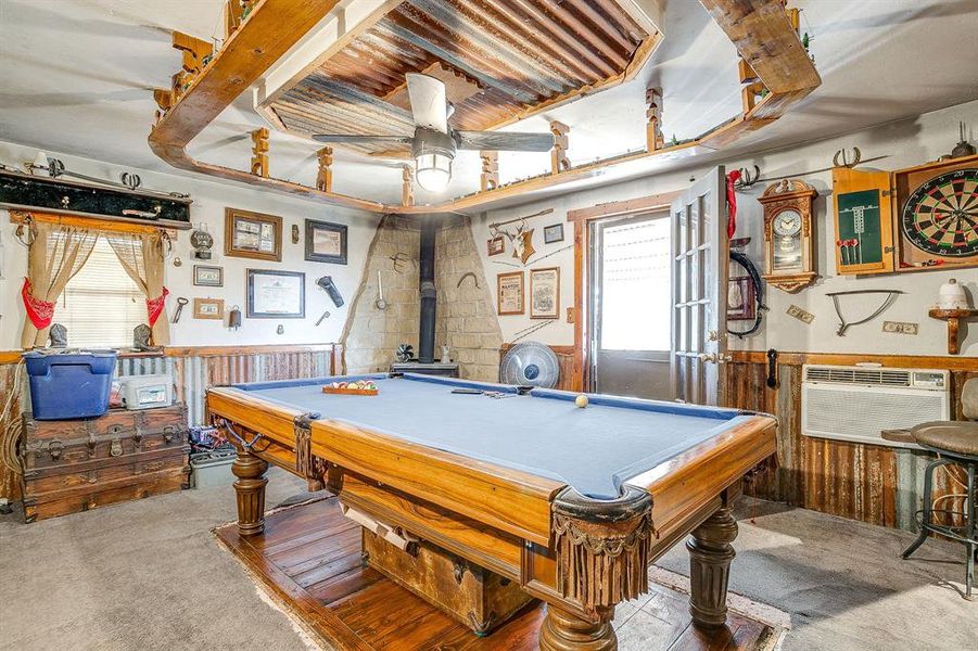 Game room with wainscoting, light colored carpet, a wood stove, billiards table, and wood walls Game room with wainscoting, light colored carpet, a wood stove, billiards table, and wood walls