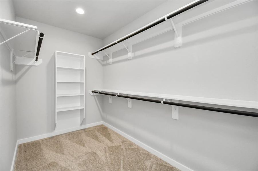 Immerse yourself in the lap of luxury within this roomy walk-in closet boasting high ceilings, built in shelves, and plush carpeting. Sample photo of completed home with similar floor plan. Actual colors and selections may vary.