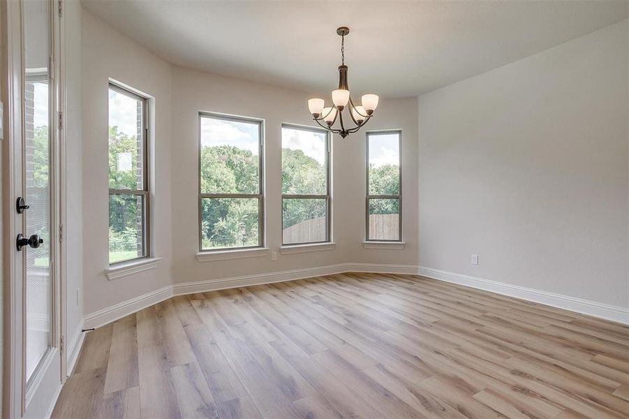 Unfurnished room with light hardwood / wood-style floors and an inviting chandelier