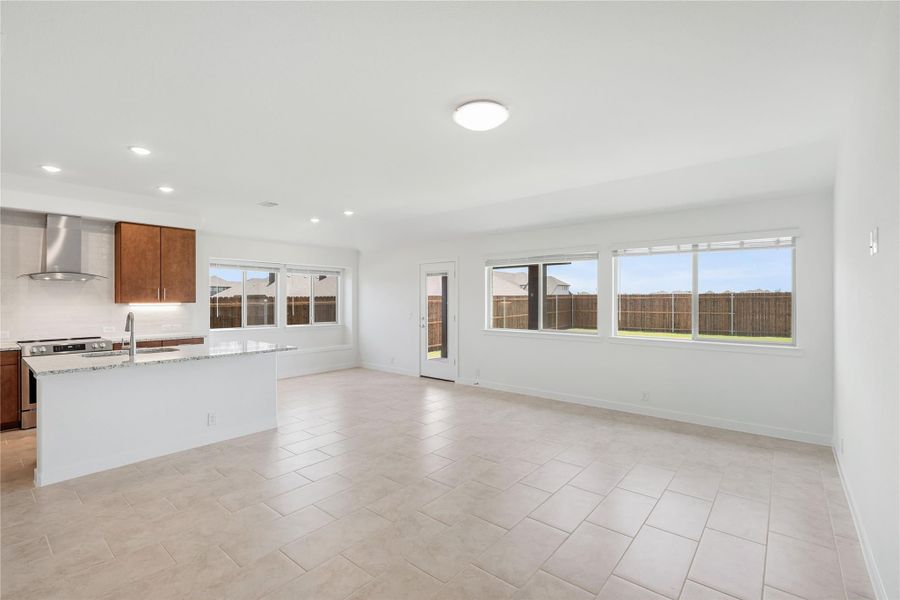 Open-concept kitchen and living area with white island, dark wood cabinets, and tile floors