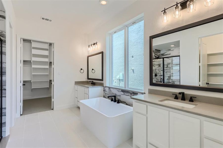 Bathroom featuring a bath to relax in, double vanity, and tile floors