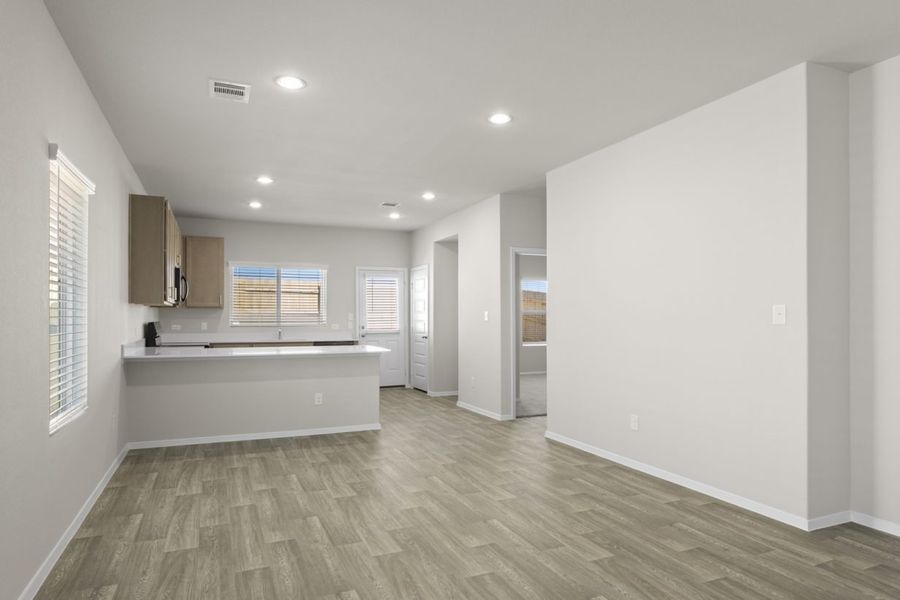 Image of a dining room with beige walls, light brown flooring, and an open U-shaped kitchen Image of a dining room with beige walls, light brown flooring, and an open U-shaped kitchen