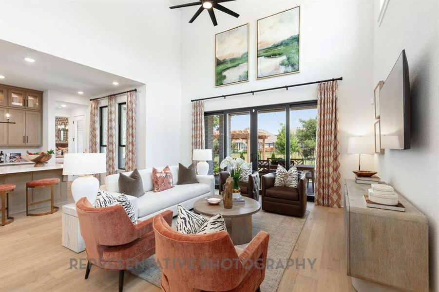 Living room featuring light wood-style floors, a high ceiling, recessed lighting, and a ceiling fan Living room featuring light wood-style floors, a high ceiling, recessed lighting, and a ceiling fan