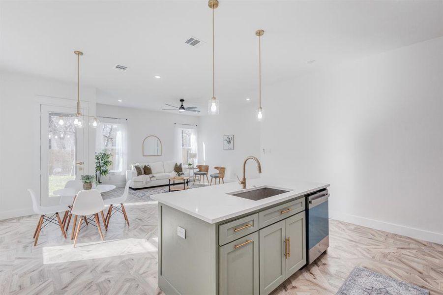 Kitchen featuring stainless steel dishwasher, ceiling fan, sink, a center island with sink, and light parquet flooring