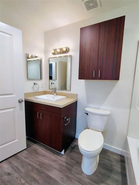 Bathroom with vanity, hardwood / wood-style flooring, toilet, and a tub