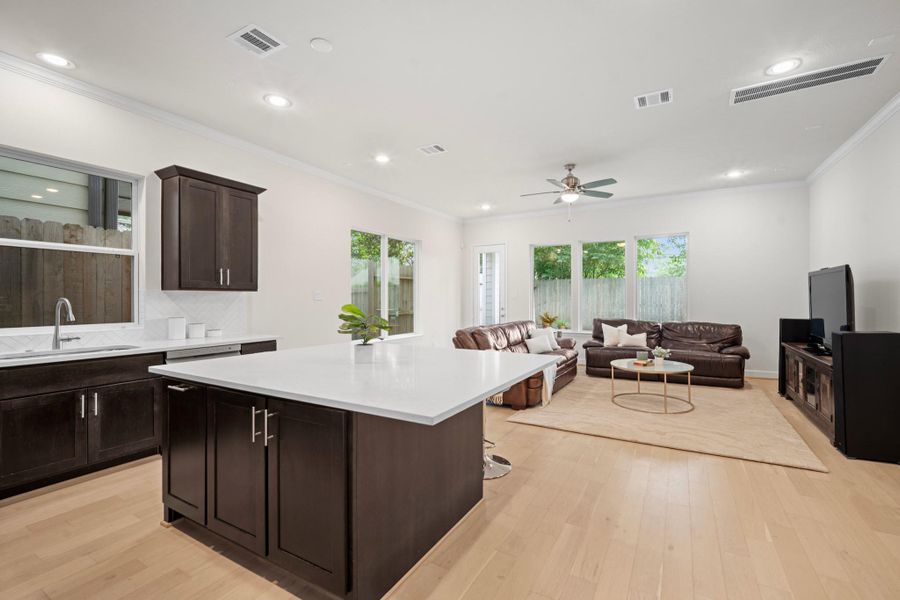 The quartz island connects kitchen to living seamlessly, with backyard views and natural light pouring in from multiple directions. The quartz island connects kitchen to living seamlessly, with backyard views and natural light pouring in from multiple directions.
