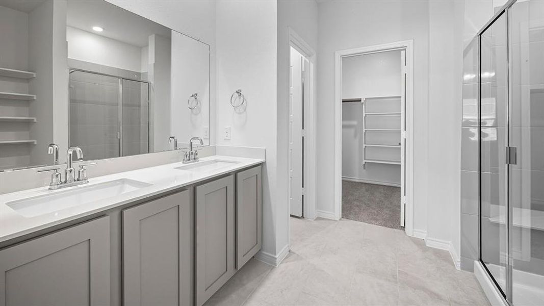 Bathroom with a spacious closet, double vanity, and a stall shower