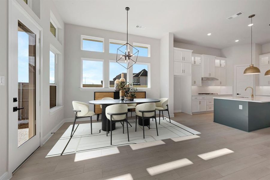 Dining space featuring healthy amount of natural light, light wood-style floors, and hanging lights Dining space featuring healthy amount of natural light, light wood-style floors, and hanging lights