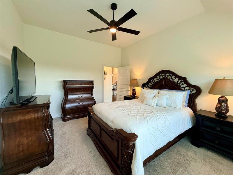 Carpeted room featuring a ceiling fan with integrated lighting, a vaulted ceiling, and an open doorway Carpeted room featuring a ceiling fan with integrated lighting, a vaulted ceiling, and an open doorway