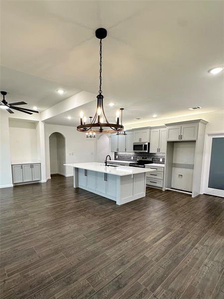 Kitchen featuring sink, tasteful backsplash, a center island with sink, appliances with stainless steel finishes, and pendant lighting