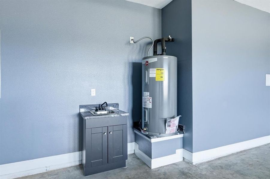 Utility room with electric water heater and a sink