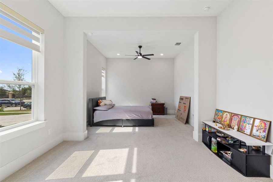 Carpeted bedroom with a ceiling fan and recessed lighting