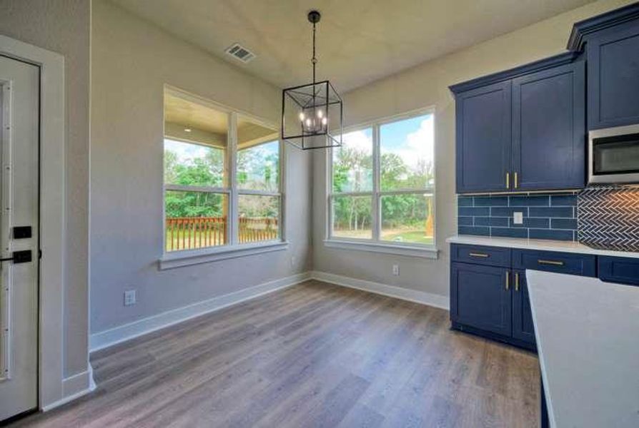 A contemporary dining area featuring abundant natural light and rich blue cabinetry, ideal for entertaining.