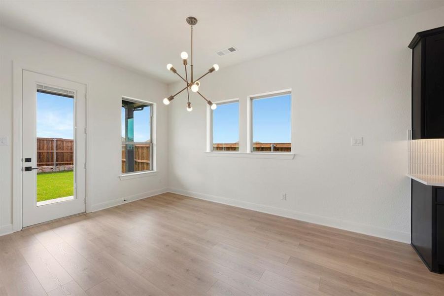 Unfurnished dining area featuring a chandelier and light wood-type flooring Unfurnished dining area featuring a chandelier and light wood-type flooring