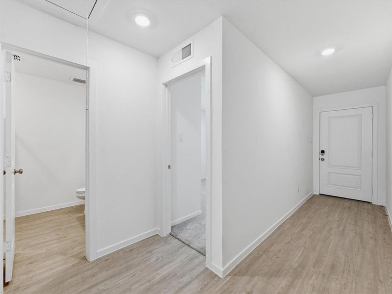 Entryway featuring wood-finish flooring, white paneled doors, recessed lighting, and crisp white walls