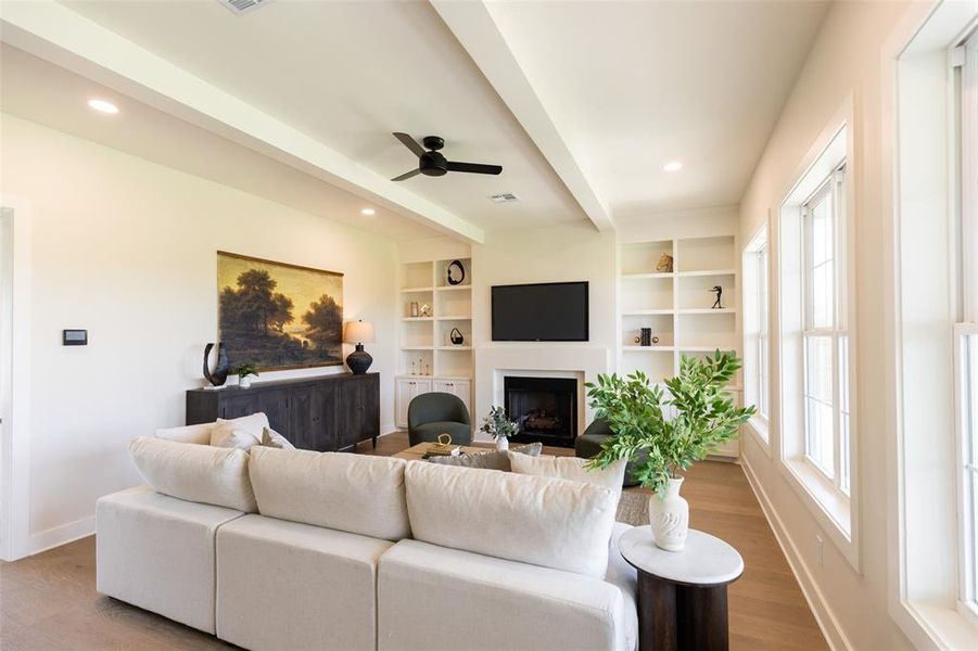 Bright living area featuring recessed lighting, a ceiling fan, wood-finish flooring, built-in shelving, and multiple windows