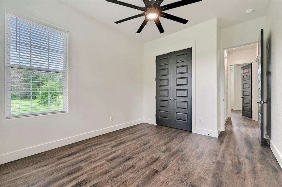 Unfurnished bedroom with a closet, baseboards, a ceiling fan, and dark wood finished floors
