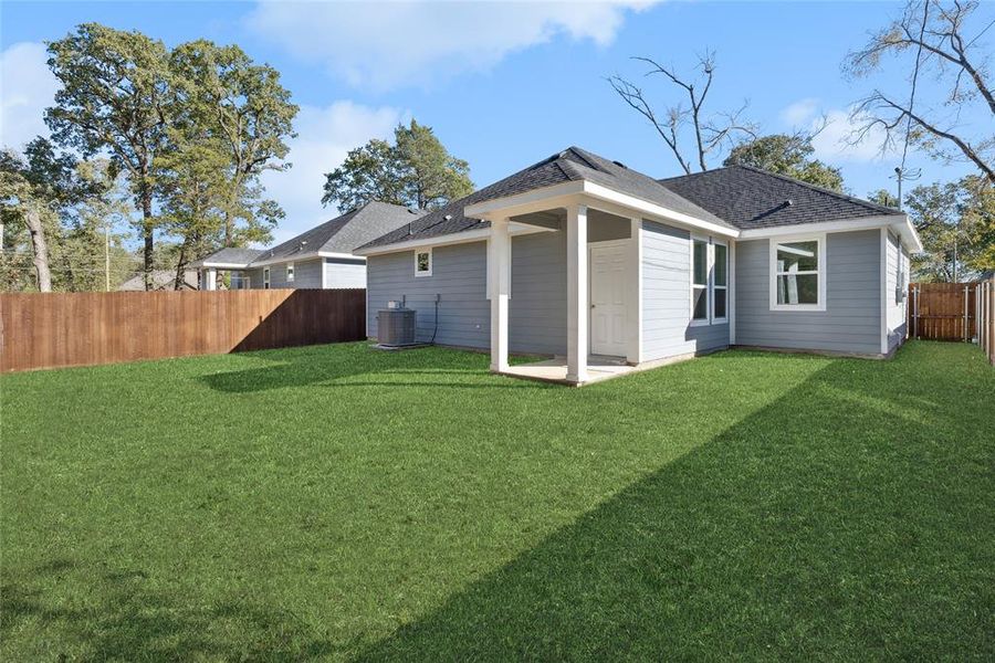 Back of house featuring central AC unit and a yard