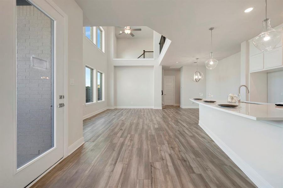 Unfurnished living room featuring a high ceiling, light wood-type flooring, ceiling fan, and recessed lighting