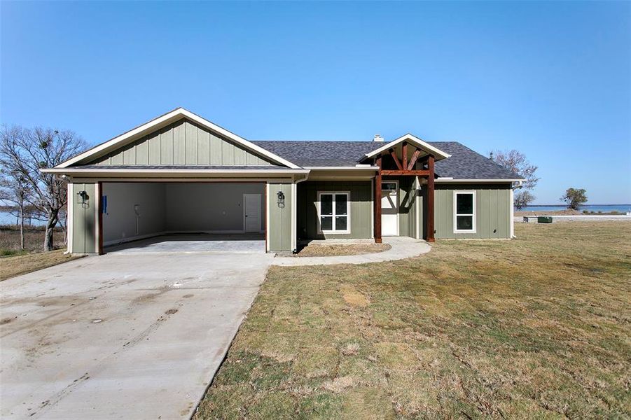 View of front of property with a front yard and a carport