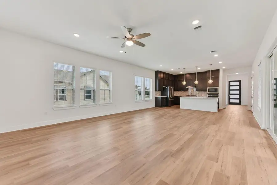 Open-concept living space featuring light wood-finish flooring, recessed lighting, and a ceiling fan