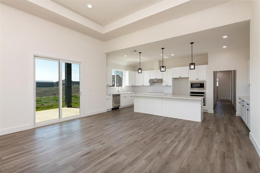 Kitchen featuring a center island, tasteful backsplash, under cabinet range hood, and stainless steel appliances
